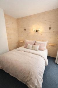 a bedroom with a large white bed with wooden walls at Le Chalet in Les Deux Alpes