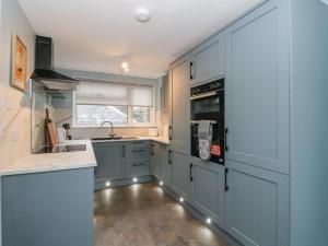 a kitchen with blue cabinets and a sink at Pirnies in Pitlochry