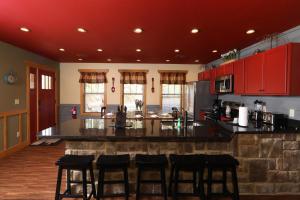 a large kitchen with red cabinets and bar stools at Firefly Nights – 5-Bed Mountain Chalet with Private Theater and Elevator in Gatlinburg
