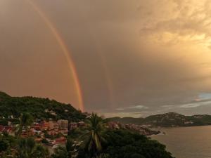 a double rainbow over a city and the water at Tuya Casita in Zihuatanejo