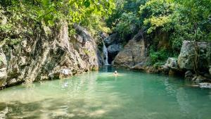 a person swimming in a river in front of a waterfall at Tuya Casita in Zihuatanejo