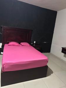 a pink bed with two pink pillows in a room at Motel Love in Altamira