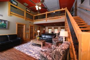 a living room with a staircase and a couch at Firefly Nights – 5-Bed Mountain Chalet with Private Theater and Elevator in Gatlinburg
