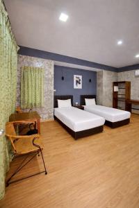 a bedroom with two beds and a chair at Na Ville Resort in Ban Huai Yai