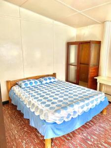 a bedroom with a bed with a blue comforter at Tamari's Rest House in Lian