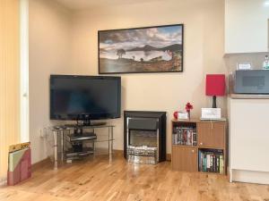 a living room with a flat screen tv and a fireplace at Thistle Dubh in Drumnadrochit