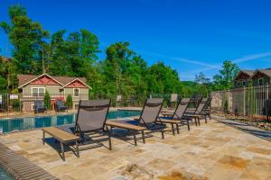 a row of chaise lounge chairs next to a pool at Gatlinburg Pool Pad – Luxury 4BR Chalet, Indoor Pool, Sauna & Theater Room in Gatlinburg