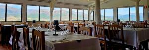 a room full of tables and chairs with mountains in the background at M&L Gerês in Salamonde