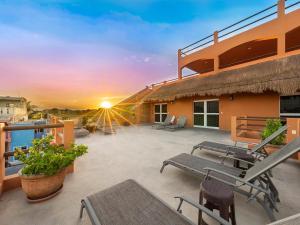 a patio with tables and chairs on a building with the sunset at Casa Bella Noche Isla Mujeres in Isla Mujeres