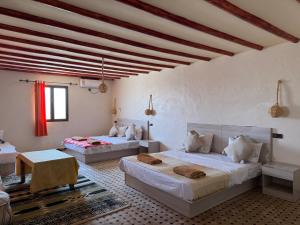 two beds in a room with white walls at Merzouga Infinity Dunes Camp in Merzouga +15 photos