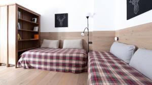 a bedroom with two beds with a plaid blanket at Plagheira 1 in Santa Caterina Valfurva