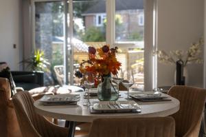 a dining room table with a vase of flowers on it at Seashells in Highcliffe