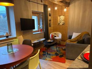 a living room with a table and a tv at Loft Cocooning et Lumineux in Arbois +10 photos