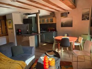 a living room with a couch and a table and a kitchen at Loft Cocooning et Lumineux in Arbois