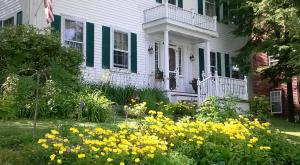 a white house with yellow flowers in the yard at Pryor House B&B in Bath