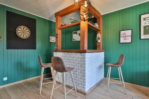 a bar with green walls and two stools at Le gîte l'écureuil in Malmedy