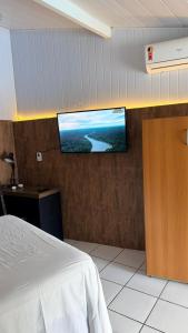 a bedroom with a flat screen tv on the wall at Woods Hostel in Belo Horizonte