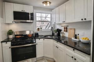 a kitchen with white cabinets and a black stove top oven at Jefferson - 20 mins to Manhattan, NYC in West New York +5 photos