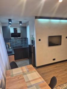 a living room with a kitchen and a table with a television at Apartament Serbinowska in Kalisz