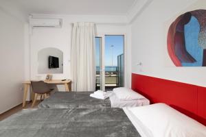 a hotel room with two beds and a desk and window at Delfini Hotel in Patra +196 photos