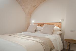 a bedroom with a white bed with white sheets and pillows at Dimore Bianche, Santa Chiara in Putignano