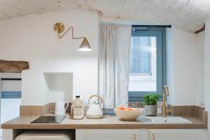 a kitchen with a counter with a sink and a window at Dimore Bianche, Santa Chiara in Putignano