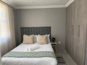 a bedroom with a large bed with white sheets and pillows at Saviour Apartments in Mthatha +2 photos