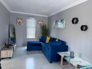 a living room with a blue couch and a table at Saviour Apartments in Mthatha