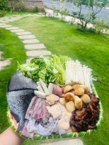 a person holding a basket of food in the grass at Mia's Homestay in Quang Ninh
