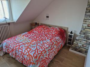 a bedroom with a bed with a red and white comforter at maison prairie in Haguenau