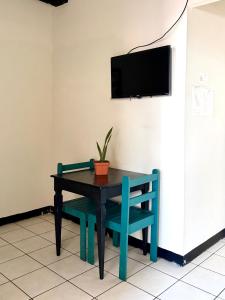 a table with two chairs and a tv on a wall at Casa Elizabeth Apartamentos in Quetzaltenango