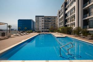 a large blue swimming pool with chairs and buildings at Nido x Gran Ciudad Nuevo Sur in Monterrey