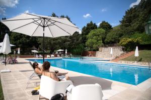 two people sitting in chairs by a pool with an umbrella at Green House in Villa General Belgrano