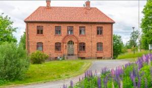 an old brick building with a field of purple flowers at Nice and cosy flat in Molkom