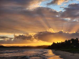 a sunset over a beach with trees and clouds at Costa Azul Apartment in Punta Santiago +4 photos