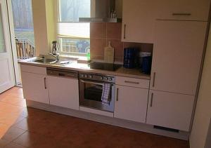 a kitchen with white cabinets and a stove top oven at Hotel Café Wahlde Restaurant in Neuenkirchen-Vörden