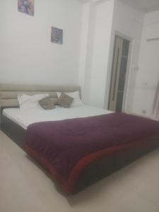 a bedroom with a large bed with purple sheets and pillows at Morisika lodge in Guwahati +3 photos