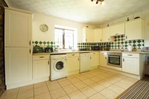 a kitchen with white cabinets and a washing machine at Bodhyfryd in Llanfairpwllgwyngyll
