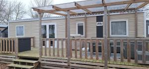 a tiny house with a deck and a pergola at Chalet Lauwersoog mét airco! in Lauwersoog