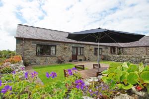 a patio with an umbrella in front of a house at Bodhyfryd in Llanfairpwllgwyngyll
