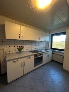 a kitchen with white cabinets and a vase of flowers on the counter at Oak Wood Ranch Guest Apartment in Marsberg