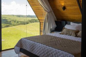 a bed in a room with a large window at Cabanas Horizonte Cambará Solare in Cambará