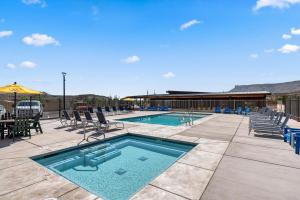 a swimming pool with chairs and a table and a building at Zion Vacation Cabins in Virgin
