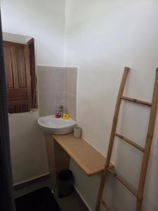 a bathroom with a sink and a wooden shelf at AK Lodge Raiatea in Raiatea