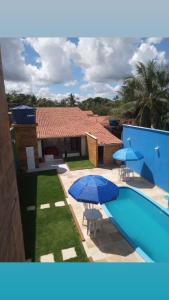 a villa with a swimming pool and two blue umbrellas at Pousada Casa do Arthur in Barreirinhas