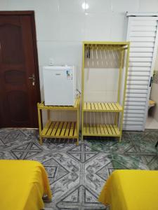 a room with two yellow benches and a refrigerator at Pousada Casa do Arthur in Barreirinhas
