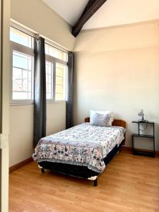 a bedroom with a bed in a room with two windows at Casa Elizabeth Apartamentos in Quetzaltenango