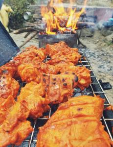 a bunch of food on a grill with flames at Peak & Pine cottage in Almora