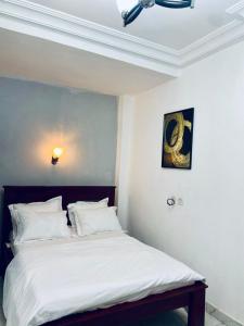 a bed with white sheets and pillows in a room at KMC Guest House in Douala