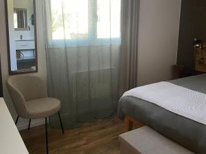 a bedroom with a bed and a chair and a window at Chez Fab in Ferrières-lès-Ray